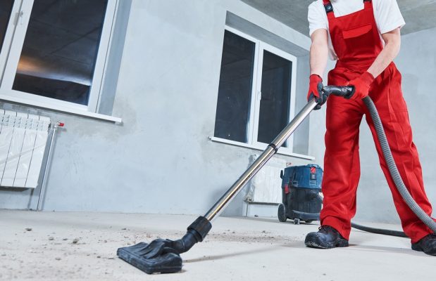 man cleaning and removing construction dust with vacuum cleaner after repair
